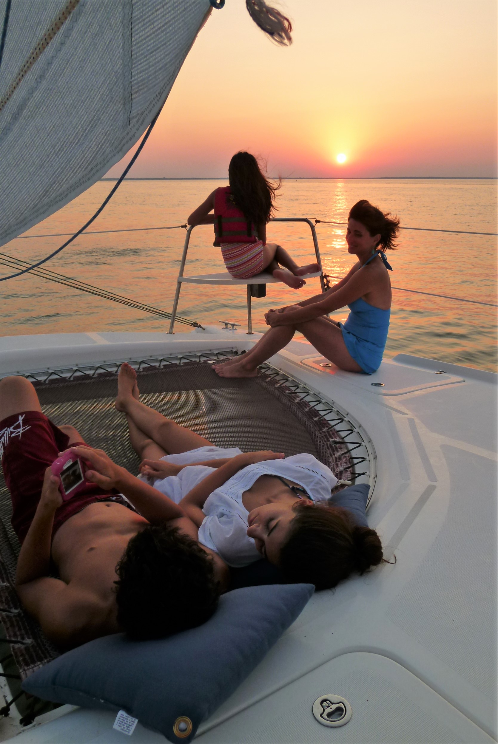 Guests relaxing on the trampoline net of Now and Zen at sunset in St Marys inlet